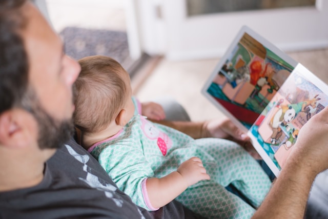 Picture of a father and a baby reading a book 